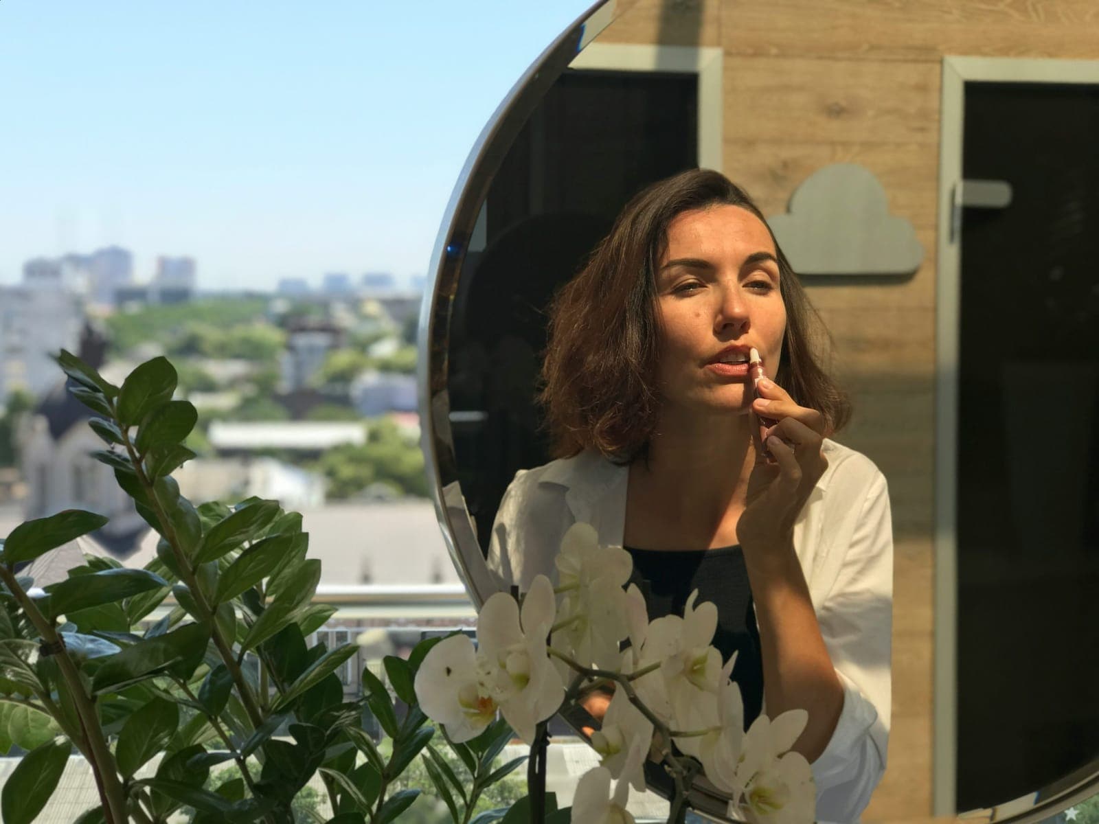 Woman applying lip balm in front of a mirror