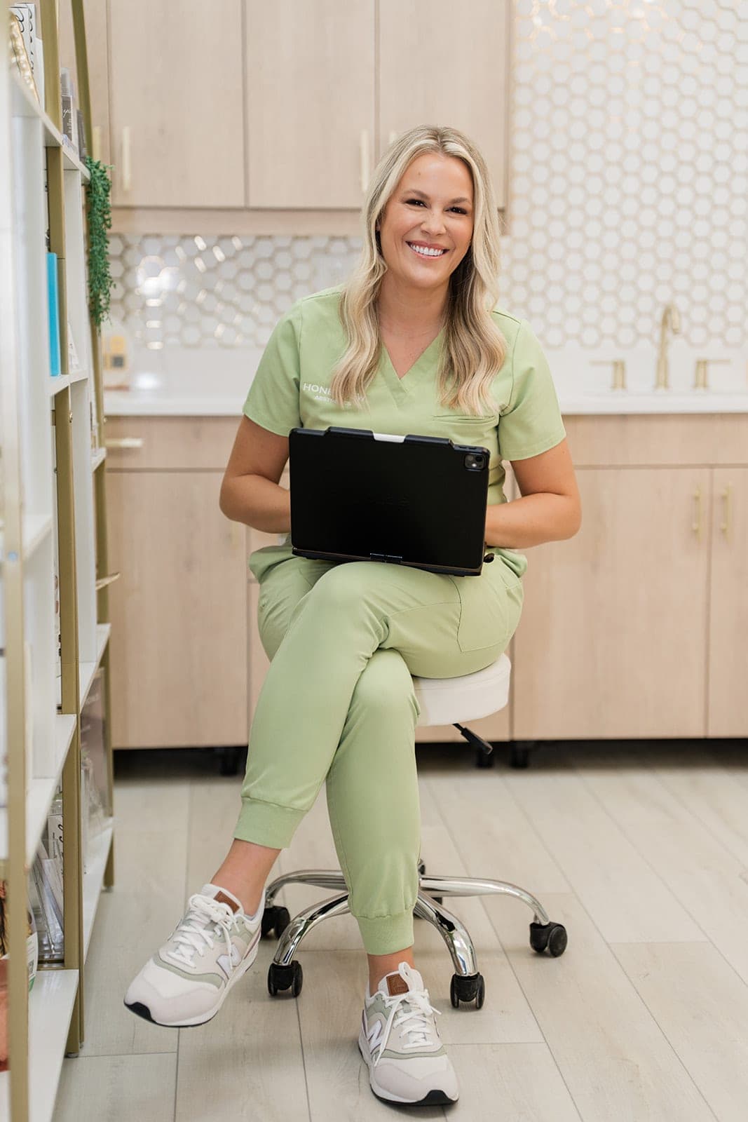 Taryn, RN, smiling with a tablet in the Honeydew Aesthetics treatment room